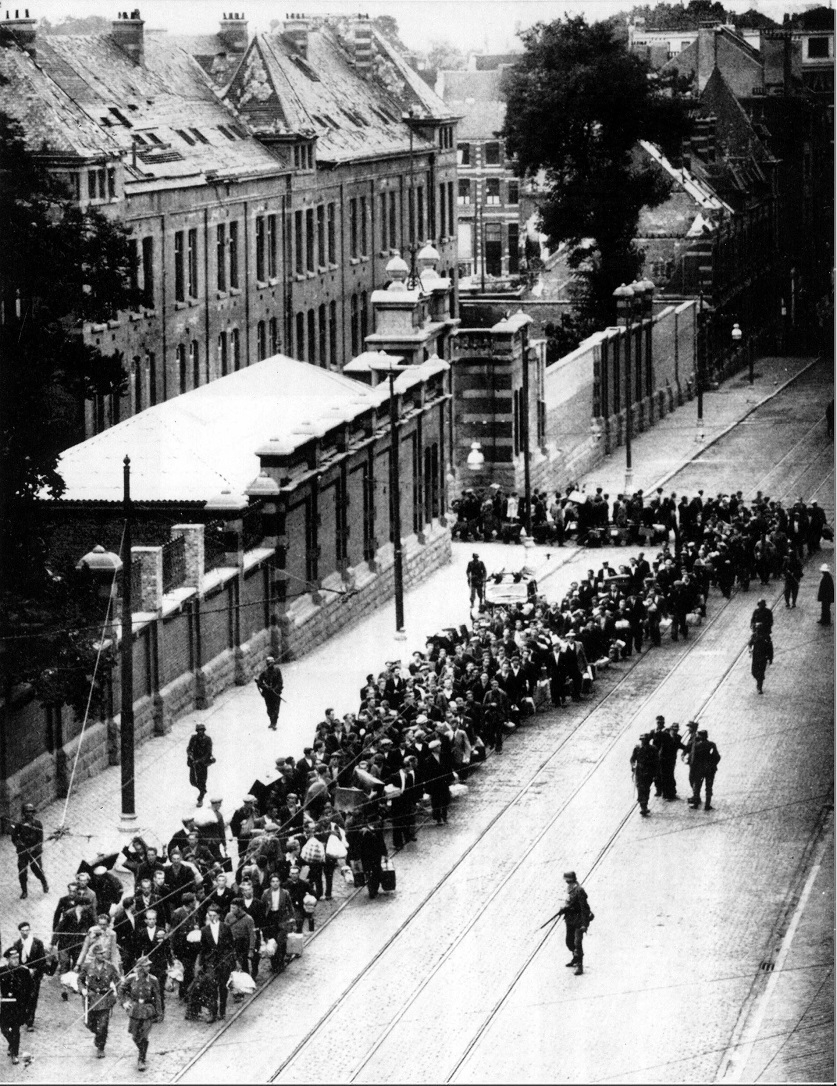 Photo clandestine d'une colonne de travailleurs forcés belges partant sous garde allemande pour leur déportation. Source: CegeSoma/Archives nationales.